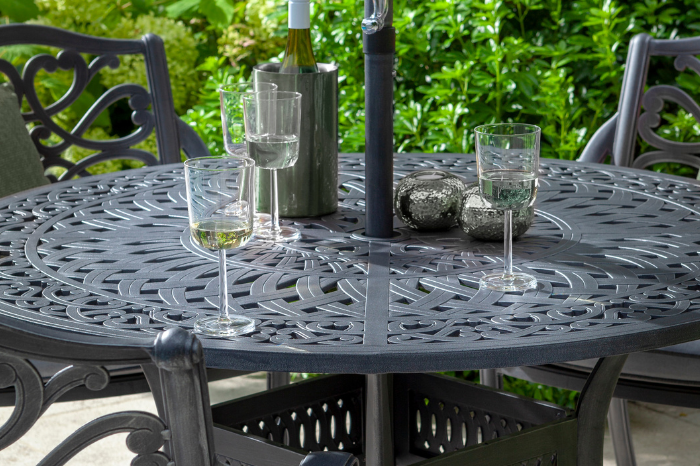Outdoor patio table with wine glasses and a bottle on a sunny day.