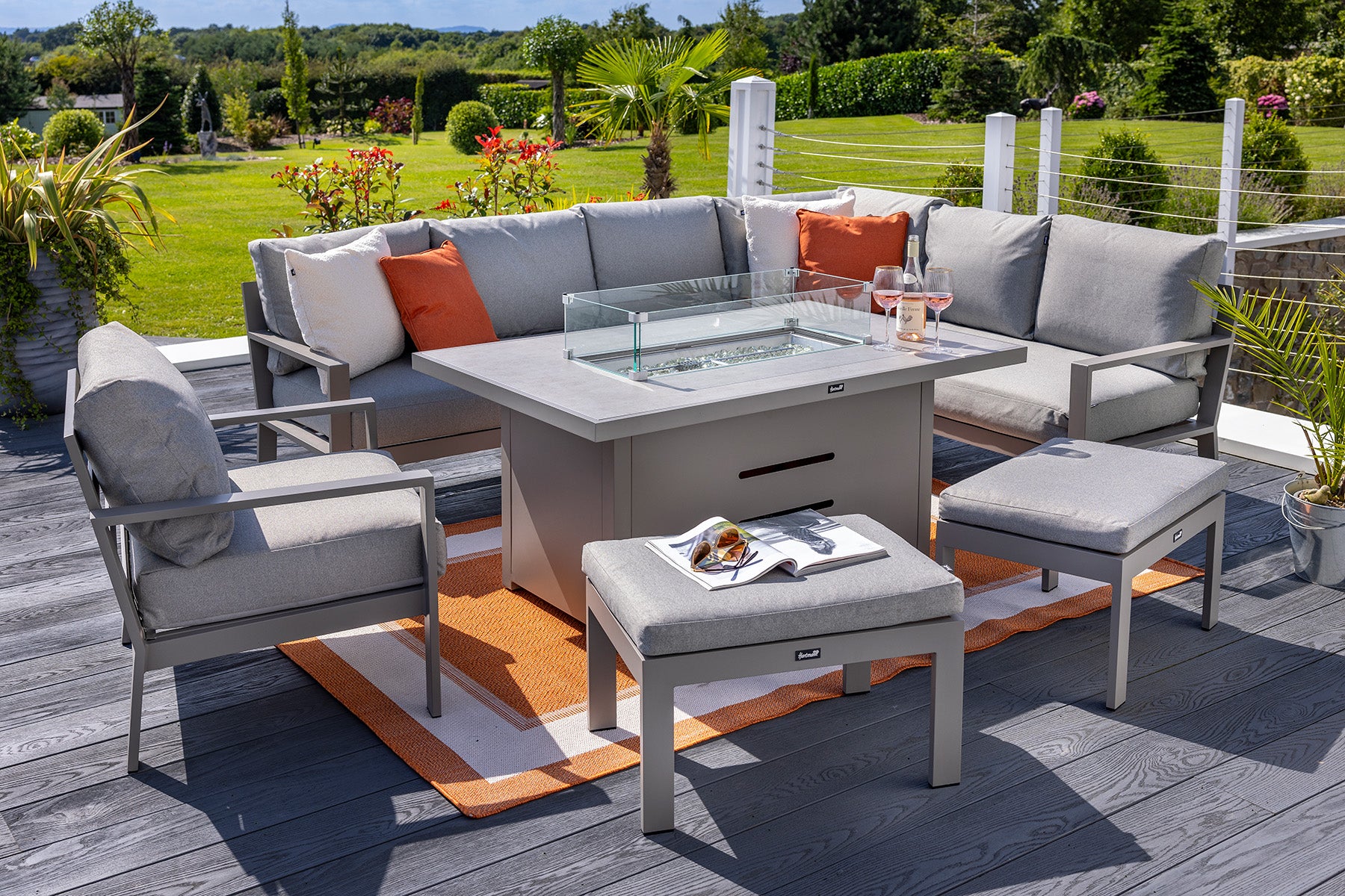 Outdoor patio set with fire pit table, chairs, and cushions on a wooden deck.