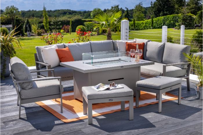 Outdoor patio set with fire pit table, chairs, and cushions on a wooden deck.