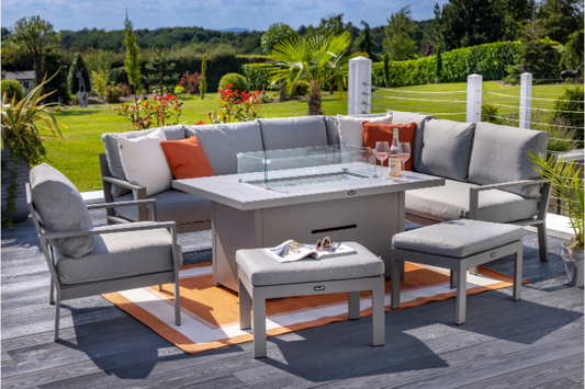 Outdoor patio set with fire pit table, chairs, and cushions on a wooden deck.