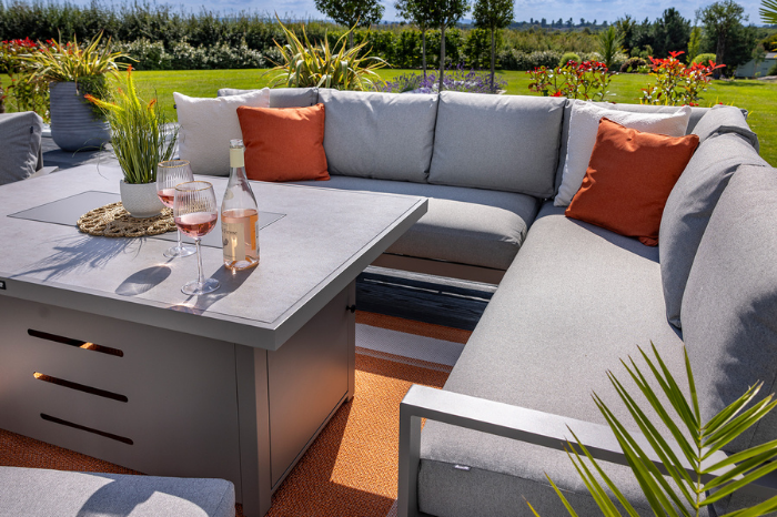 Outdoor patio set with sectional sofa, table, and decorative items on a sunny day.