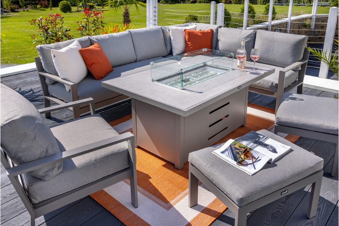 Outdoor patio set with sectional sofa, fire pit table, and chairs on a wooden deck.