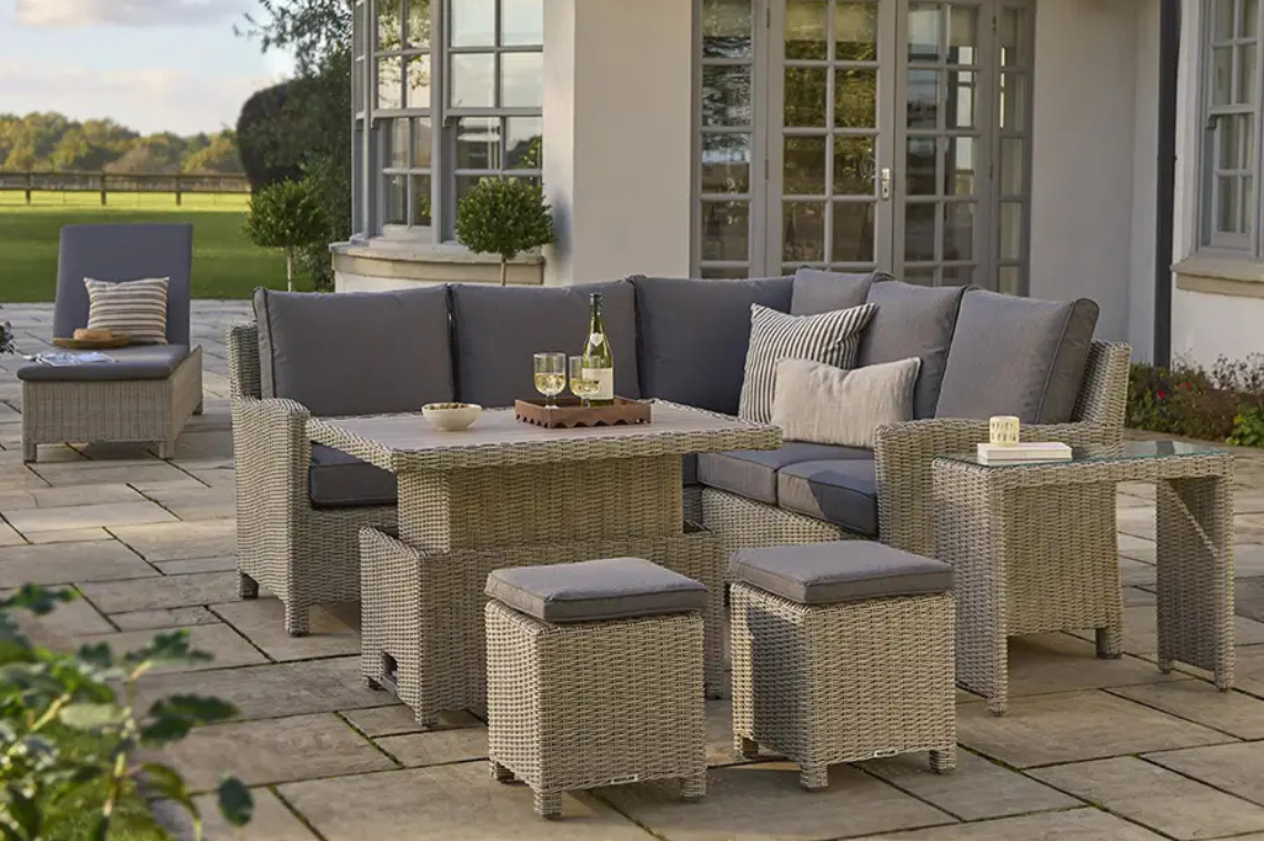 Outdoor patio furniture set, the Kettler Palma Mini corner with grey cushions on a stone patio.