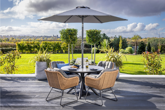 Hartman Rayo 4 seat round dining set with lava ceramic table and parasol in a garden setting