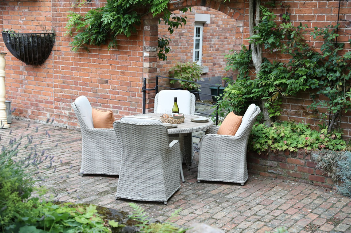 Supremo Hemsby 4 seat round dining set with parasol in a garden setting